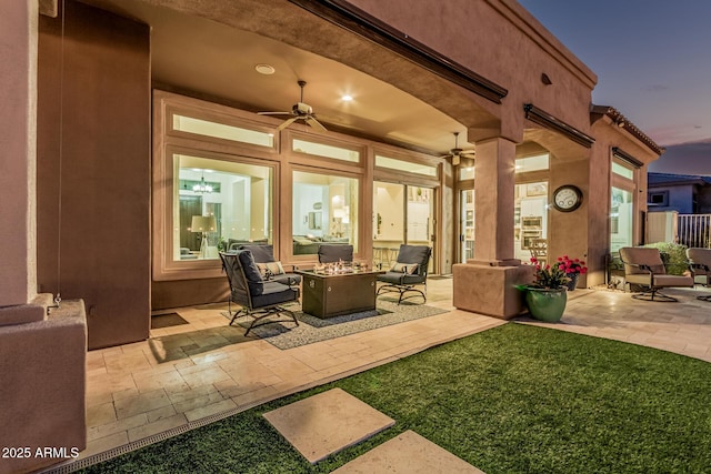 view of patio / terrace featuring ceiling fan and an outdoor living space with a fire pit