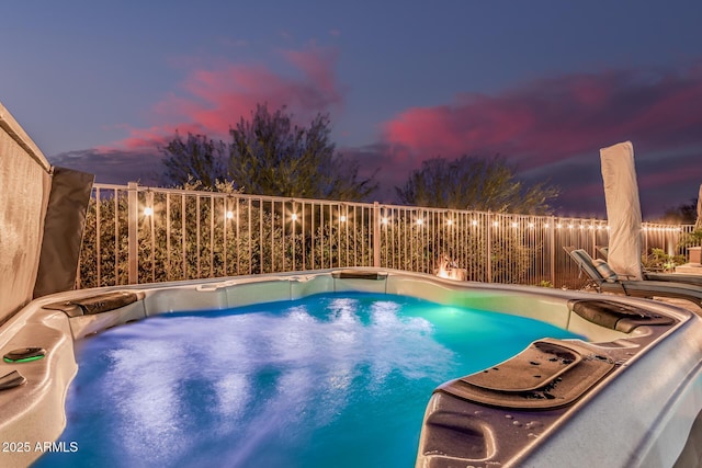 view of swimming pool featuring a hot tub and fence