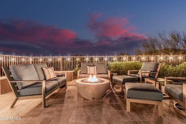 patio terrace at dusk featuring fence and an outdoor living space with a fire pit