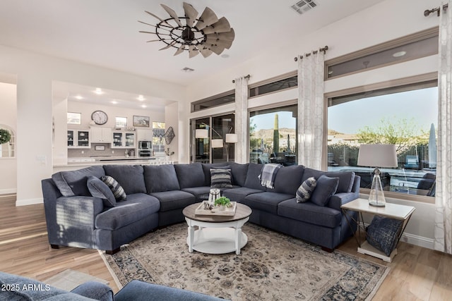 living area with baseboards, visible vents, and light wood-style floors