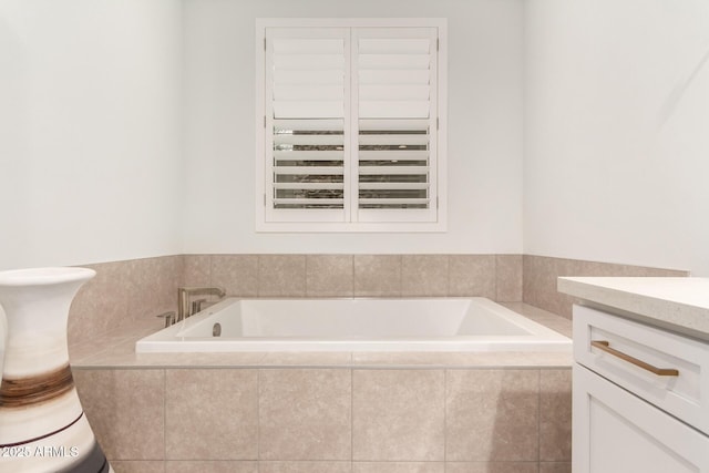 bathroom with tiled tub and vanity