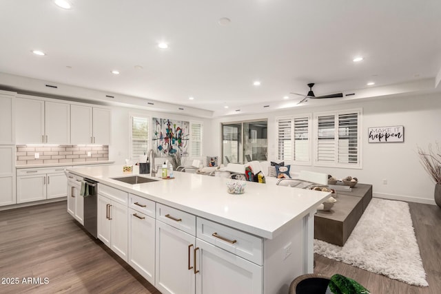 kitchen featuring stainless steel dishwasher, a kitchen island with sink, sink, and white cabinets