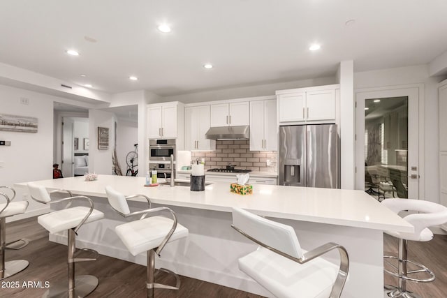 kitchen featuring a spacious island, white cabinetry, stainless steel appliances, and a breakfast bar