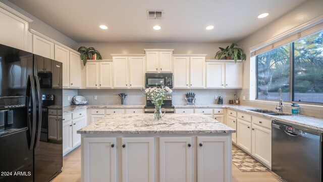 kitchen featuring white cabinets, a center island, sink, and black appliances