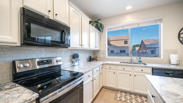 kitchen featuring light stone countertops, sink, white cabinets, and black appliances