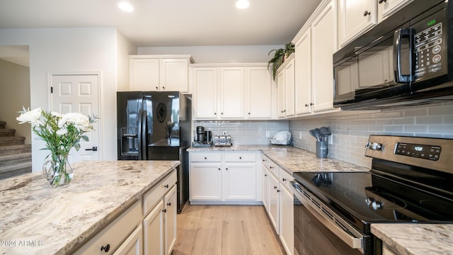 kitchen with tasteful backsplash, light stone countertops, white cabinets, and black appliances