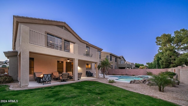 back of property featuring a lawn, a fenced in pool, ceiling fan, a balcony, and a patio