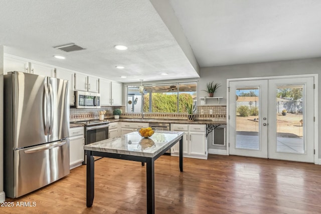 kitchen featuring visible vents, a sink, white cabinets, appliances with stainless steel finishes, and backsplash