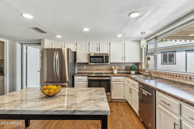 kitchen featuring white cabinets, light wood finished floors, visible vents, and appliances with stainless steel finishes