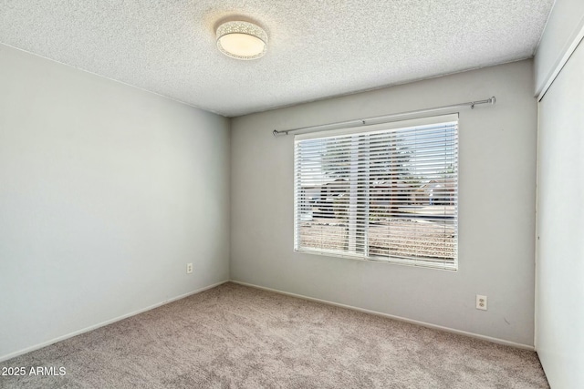 carpeted empty room featuring a textured ceiling