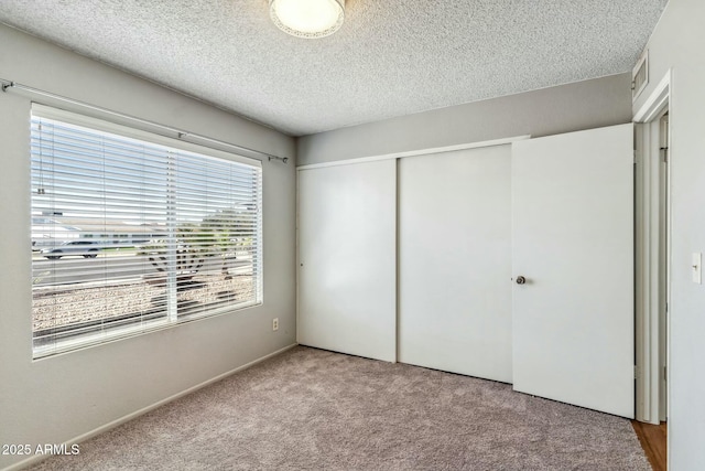 unfurnished bedroom featuring a closet, carpet, visible vents, and a textured ceiling