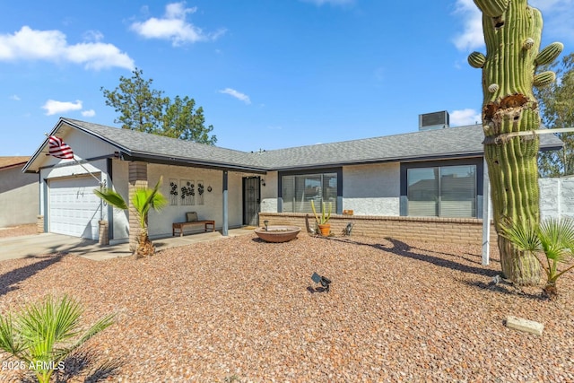 single story home featuring driveway, roof with shingles, an attached garage, stucco siding, and brick siding