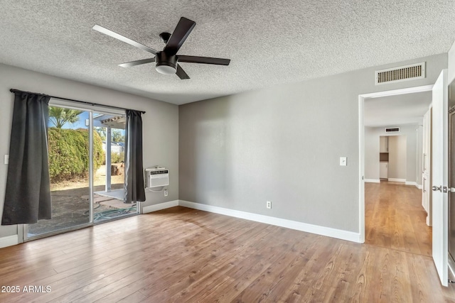 spare room with wood finished floors, visible vents, and a wall mounted AC