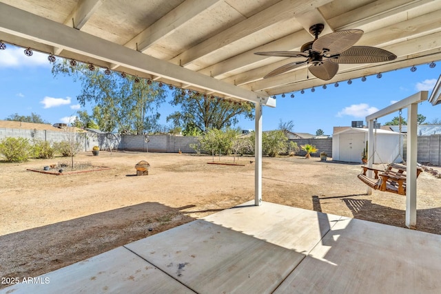 view of patio / terrace featuring an outbuilding, ceiling fan, a storage unit, and a fenced backyard