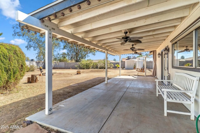 view of patio / terrace featuring ceiling fan, a storage unit, a fenced backyard, and an outdoor structure