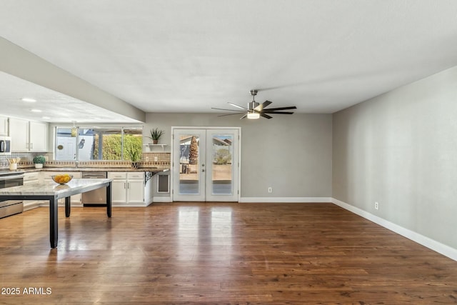 unfurnished living room with dark wood finished floors, ceiling fan, french doors, and baseboards