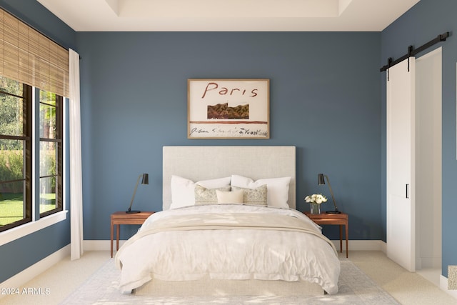 carpeted bedroom with a barn door and a raised ceiling