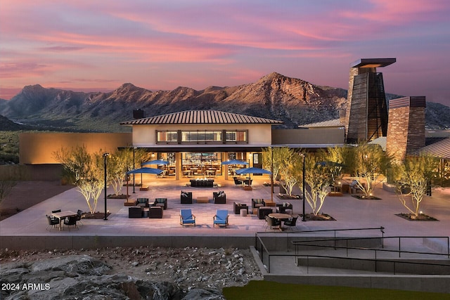 back house at dusk featuring a mountain view, an outdoor living space, and a patio area