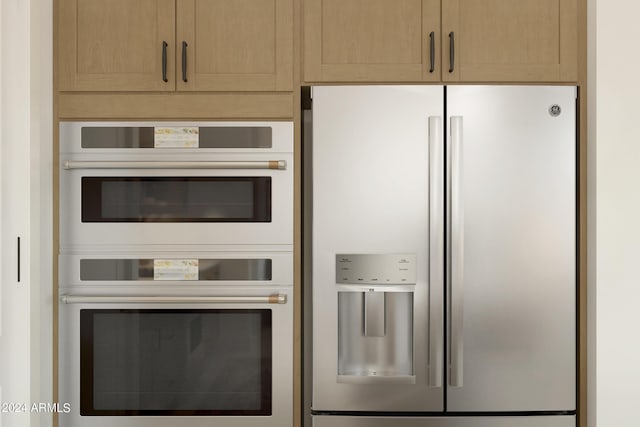 kitchen featuring multiple ovens, light brown cabinetry, and white fridge with ice dispenser