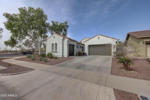 mediterranean / spanish-style house featuring driveway, an attached garage, a tile roof, and stucco siding