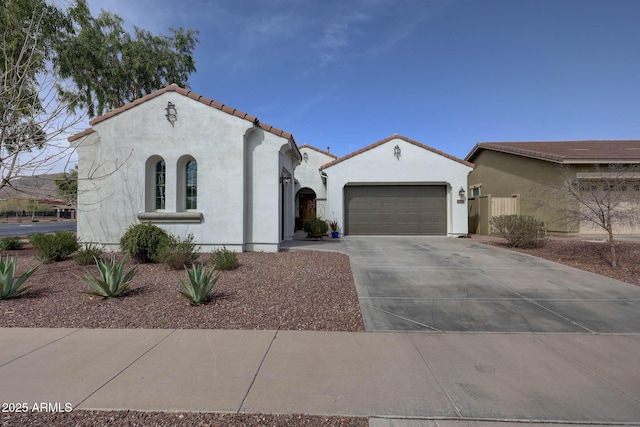 mediterranean / spanish-style home with a garage, fence, driveway, a tiled roof, and stucco siding