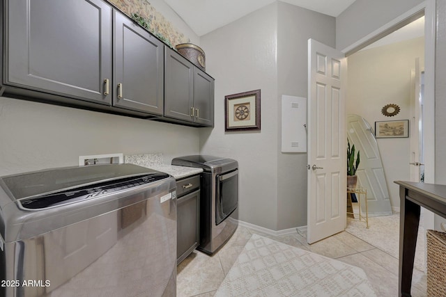 laundry room with light tile patterned floors, separate washer and dryer, cabinet space, and baseboards