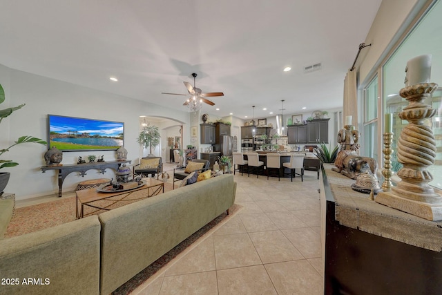 living area featuring light tile patterned floors, visible vents, arched walkways, a ceiling fan, and recessed lighting