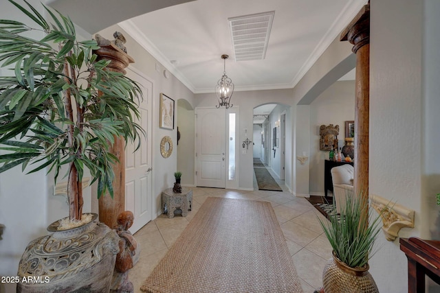 foyer featuring arched walkways, visible vents, crown molding, and light tile patterned floors