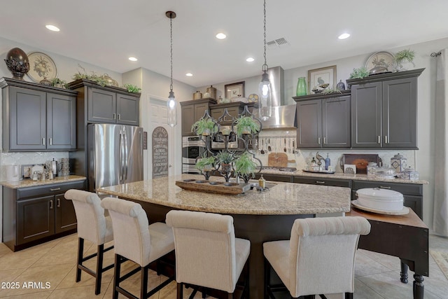 kitchen featuring light tile patterned floors, light stone counters, stainless steel appliances, visible vents, and wall chimney range hood