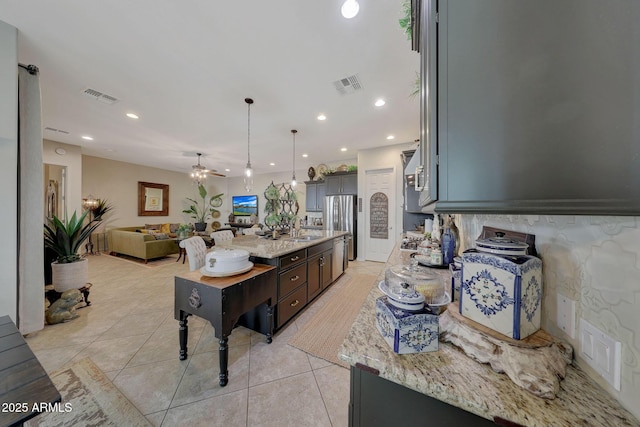 kitchen featuring open floor plan, freestanding refrigerator, light tile patterned floors, and visible vents