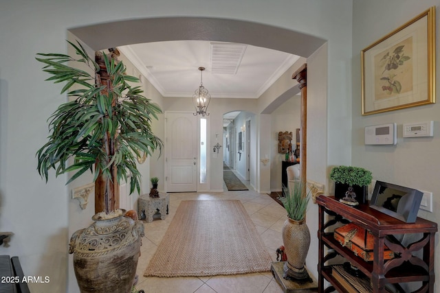 foyer entrance featuring arched walkways, light tile patterned floors, visible vents, ornamental molding, and baseboards