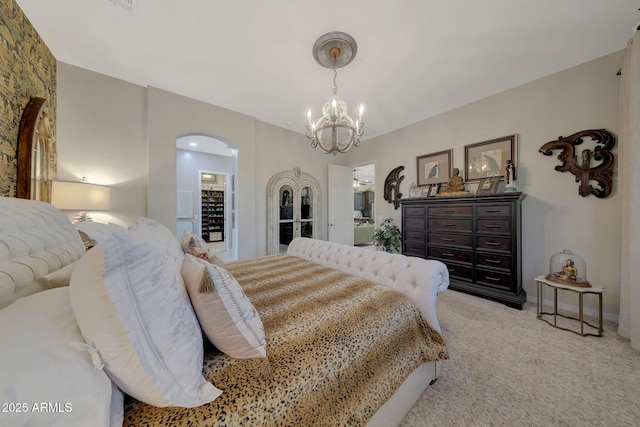 bedroom featuring arched walkways, light colored carpet, a notable chandelier, and ensuite bathroom