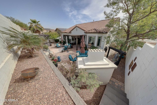 back of house featuring a patio area, a fenced backyard, stucco siding, and a tiled roof