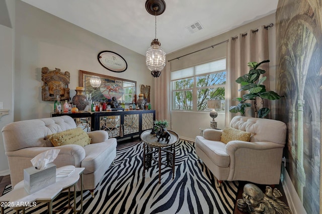 living area featuring an inviting chandelier, baseboards, visible vents, and wood finished floors