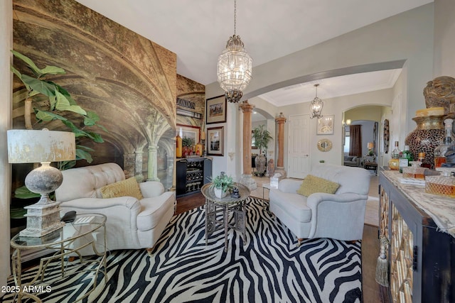 living room with an inviting chandelier, arched walkways, crown molding, and wood finished floors