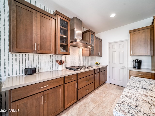 kitchen featuring decorative backsplash, light tile patterned floors, stainless steel gas cooktop, and wall chimney range hood