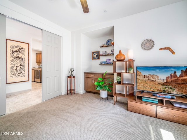 sitting room featuring separate washer and dryer, light carpet, and ceiling fan