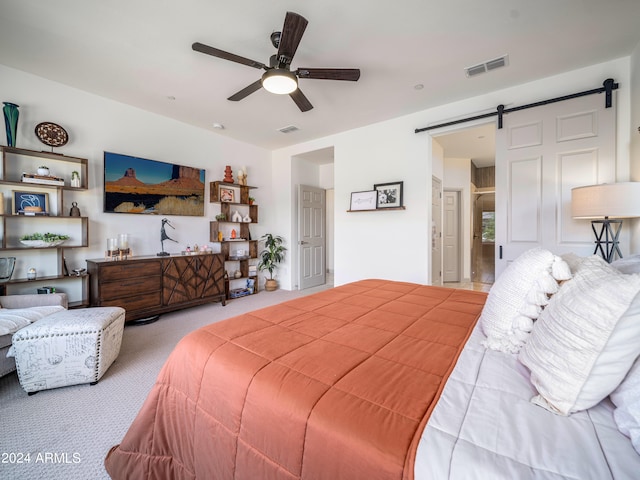 bedroom featuring a barn door, ceiling fan, and light colored carpet