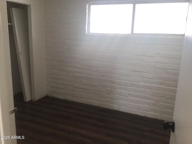 interior space featuring dark hardwood / wood-style flooring and brick wall