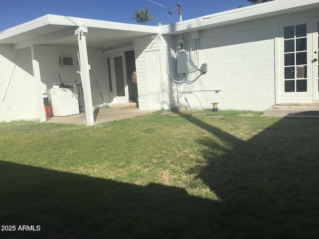 back of property featuring a wall mounted air conditioner and a lawn