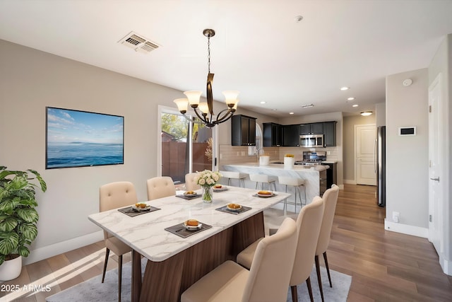 dining area featuring dark wood-type flooring and an inviting chandelier