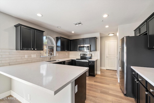 kitchen featuring decorative backsplash, kitchen peninsula, sink, and appliances with stainless steel finishes