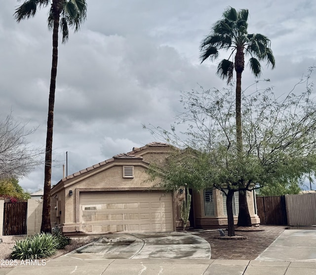 view of front facade with fence, stucco siding, concrete driveway, a garage, and a tile roof