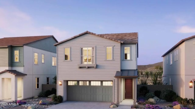 view of front of property featuring driveway, an attached garage, metal roof, fence, and a standing seam roof