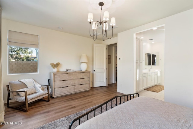 bedroom with light hardwood / wood-style floors, an inviting chandelier, and ensuite bath