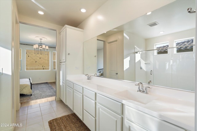 bathroom featuring tile patterned flooring, vanity, a shower with shower door, and a chandelier