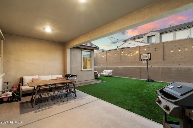 patio terrace at dusk featuring outdoor lounge area, area for grilling, and a lawn