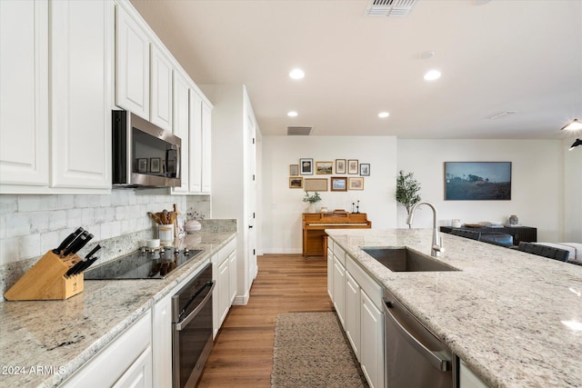 kitchen with appliances with stainless steel finishes, light hardwood / wood-style floors, white cabinetry, and sink