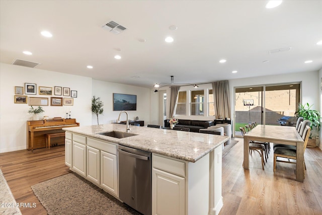 kitchen with sink, light stone counters, stainless steel dishwasher, light hardwood / wood-style floors, and a center island with sink