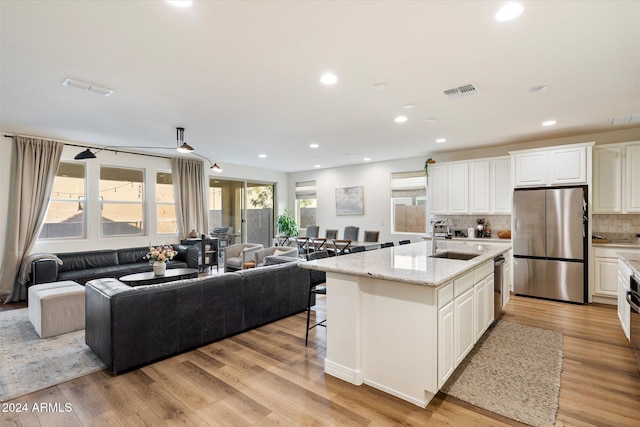 kitchen with a center island with sink, sink, appliances with stainless steel finishes, and light hardwood / wood-style flooring